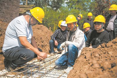 在湖南省常德市安鄉(xiāng)縣一建筑工地，技師（左一）向工人們講解扎筋技巧。新華社記者 周勉攝