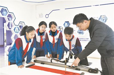 在山東日照金海岸小學(xué)，老師指導(dǎo)學(xué)生練習(xí)機(jī)械臂毛筆書寫編程。新華社記者 郭緒雷攝