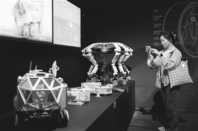 圖為觀眾觀看“宇宙考古：時空探索”展覽上展示的月面多功能平臺及智能火星探測器模型。本報記者 洪星攝